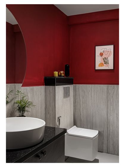 Even the restroom is designed with flair. A bold red wall is paired with textured grey tiles and a modern vessel sink, continuing the salon's sophisticated and daring color palette.