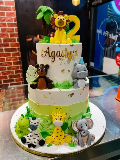 A two-tier safari animal cake for Agastya's 2nd birthday, with adorable fondant figures of a lion, hippo, elephant, and more.