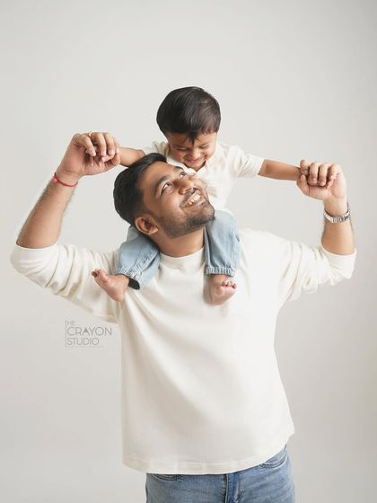 A father and son share a laugh, with the little one enjoying the view from his dad's shoulders.