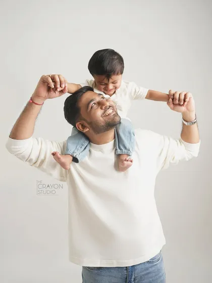 A father and son share a laugh, with the little one enjoying the view from his dad's shoulders.