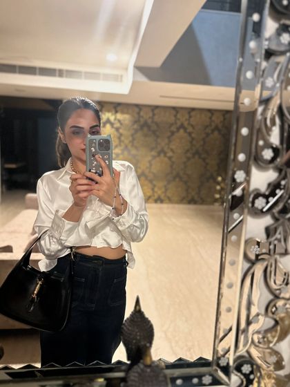 A mirror selfie showing a classic dinner outfit: a white satin shirt with dark jeans. It's an effortlessly chic combination.