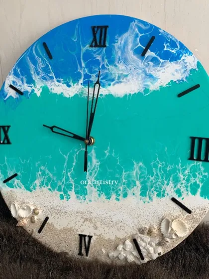 This ocean clock has a beautiful teal color and a sandy shore with carefully placed shells.