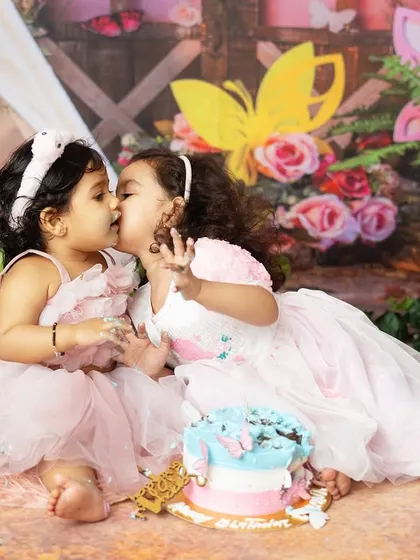A sweet kiss between sisters during the birthday celebration. It's so special when older siblings can join in on the cake smash fun.