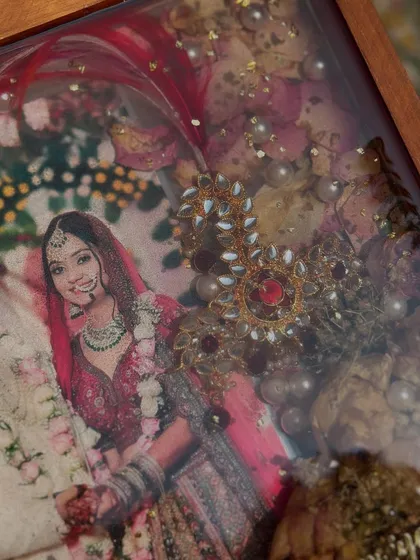 A close-up of a teakwood frame preserving a bride's photo along with her beautiful wedding jewelry. The details of the jewelry are captured perfectly in the resin.