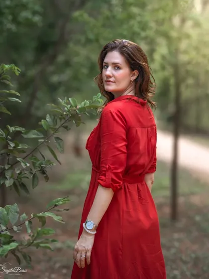 The classic "look back" pose, captured in a beautiful natural setting. The soft, dappled light filtering through the trees creates a romantic and timeless feel. This is a perfect example of an elegant outdoor portrait.