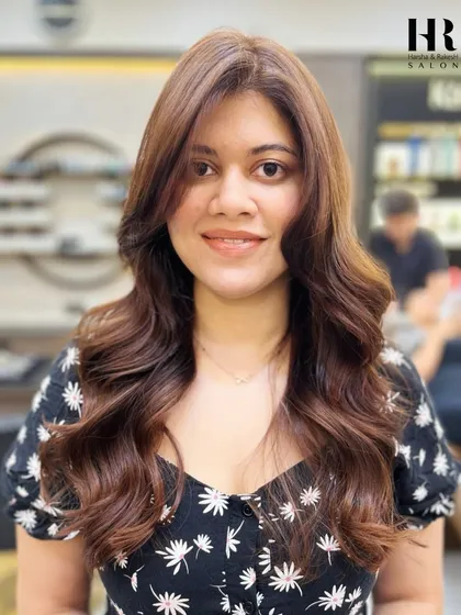 A happy client showing off her new global color. The warm brown shade is styled with soft waves and looks incredibly healthy.