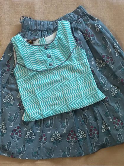 This block-printed paavada set features a lovely peacock print. The top has a back opening for easy wear, and the skirt has an elastic waist and a pocket for little treasures.