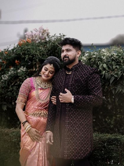A candid, happy moment captured in a garden setting. The couple's relaxed smiles and body language show their easy comfort with each other.