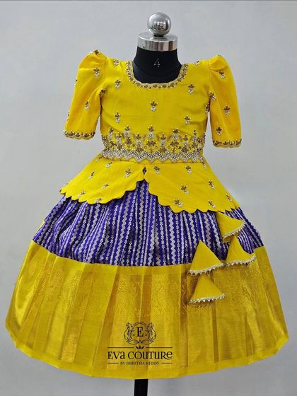 A bright yellow and blue Ikat-style lehenga. The blouse has a scalloped peplum design, and the skirt has a striped pattern.
