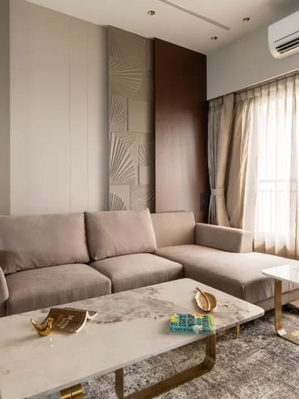 This contemporary living room stands out with its unique feature wall, adorned with a geometric designer MDF panel that adds texture and visual intrigue. Paired with a rich wooden accent and soft neutral tones, the design creates a perfect balance of elegance and warmth.