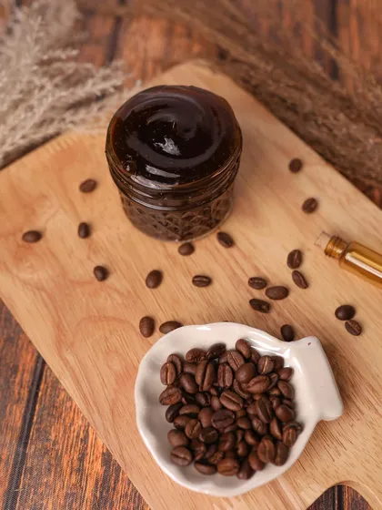 A DIY coffee scrub styled on a wooden board with coffee beans. The rustic and earthy tones perfectly match the product's main ingredient.