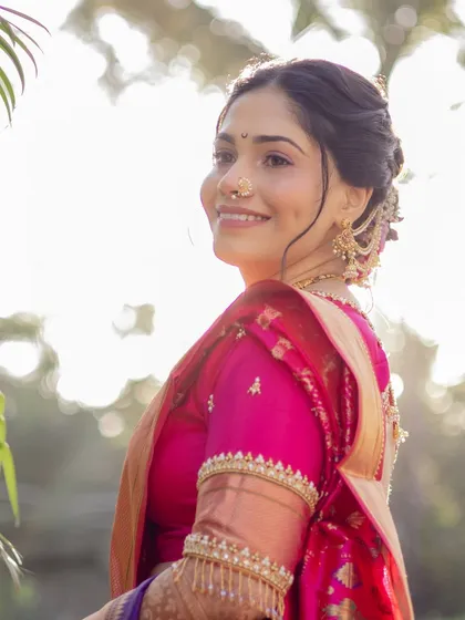 A beautiful profile shot against the light, showcasing the bride's elegant hairstyle and the rich texture of her silk saree.