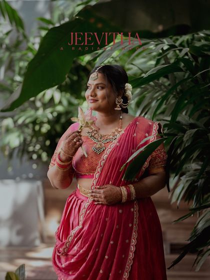 A portrait of a bride in a beautiful pink lehenga, holding a lotus flower on her betrothal day.