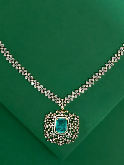 For a touch of modern luxury, I offer pieces like this stunning American Diamond and emerald-style necklace. The brilliant-cut stones are set in a floral pattern, leading to a magnificent centerpiece that makes a bold statement. This is the perfect accessory for cocktail parties or formal receptions.