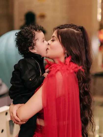 A mother's sweet kiss for her son. This close-up shot from a birthday party captures a tender, candid moment of love between them.