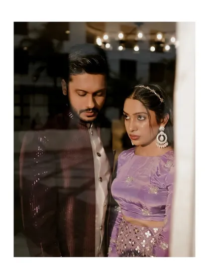 An artistic shot of the couple seen through a window, creating a sense of intimacy and romance.