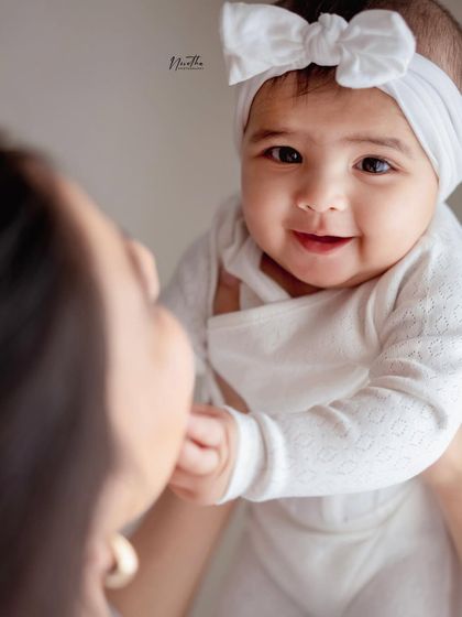 A close-up of a mother holding her baby, both looking at each other.