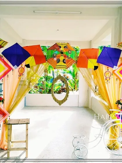 A playful and vibrant entrance designed for a pre-wedding celebration. This themed decor uses colorful kites, decorative umbrellas, and a vintage-style bicycle to create a fun, festive atmosphere that welcomes guests with a unique touch.