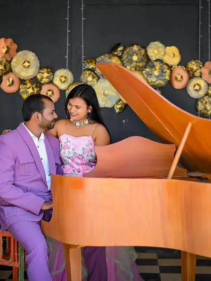 A stylish and unique pre-wedding photo featuring a couple at a grand piano. The groom looks lovingly at the bride in this creative indoor setup, showcasing a shared moment of musical romance.