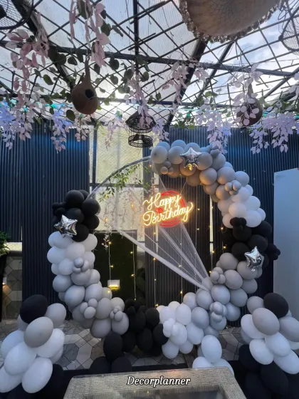 This elegant black, white, and grey balloon arch creates a sophisticated frame for a birthday celebration at a cafe. The addition of a neon sign and delicate draping adds a soft, stylish touch, proving that birthday decor can be both fun and incredibly chic.