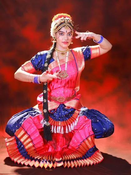This is all about the storytelling through mudras, or hand gestures. The lighting is set up to sculpt the dancer's form and highlight the vibrant colors of her costume against the dark, moody backdrop.