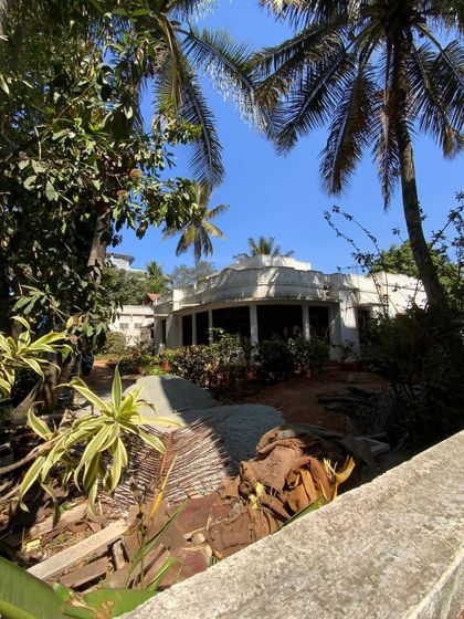 An exterior view of the century-old villa in Mysore, surrounded by lush greenery. This project is a delicate puzzle of preserving history while reinventing the space for modern life.