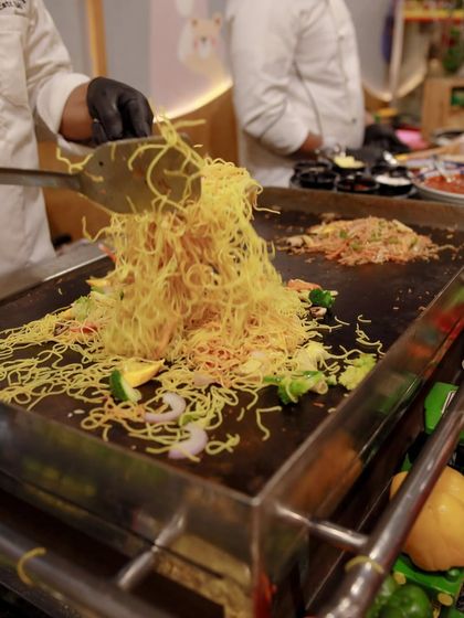 A close-up of the delicious noodles being tossed on the grill. The sights and sounds of our live cooking stations add a dynamic element to the party atmosphere.