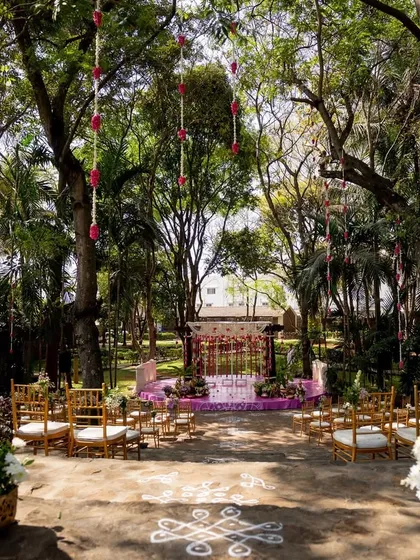 An outdoor wedding ceremony set amidst nature. I designed the aisle with traditional rangoli patterns leading to the mandap, ensuring the entire space felt like a serene, open-air temple for the couple's union.