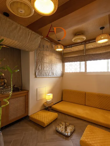 This serene meditation room is designed for tranquility, with low floor seating in a warm yellow, rattan-front cabinets, and soft, ambient lighting.