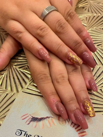 Muted brown, coffin-shaped nails with a striking accent. The ring fingers feature a textured gold foil design that adds a touch of modern art to the set.