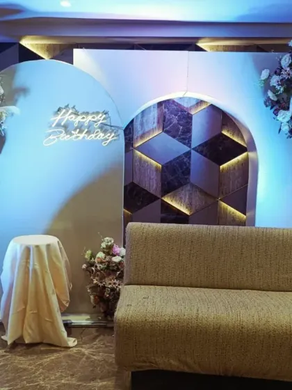This is a clean and stylish backdrop I created for an adult's birthday party. The design uses modern arched panels, a custom 'Happy Birthday' neon sign, and beautiful floral arrangements, perfect for a sophisticated and contemporary celebration.