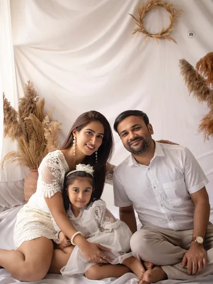 A lovely family photo from a fifth birthday session. The all-white outfits and the soft, neutral boho background create a light and airy feel.