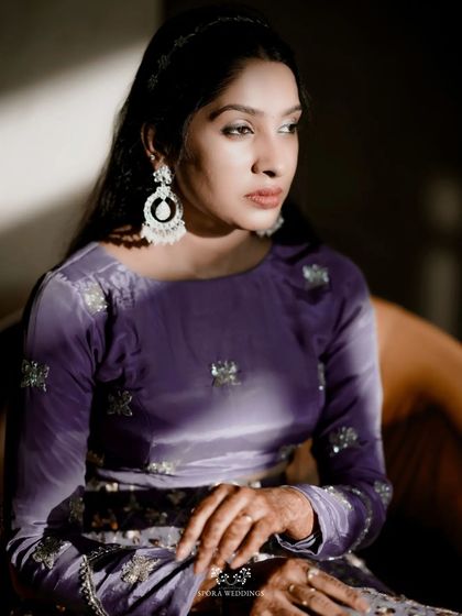 A close-up portrait of the bride in a stunning purple velvet outfit, the light catching her features beautifully.