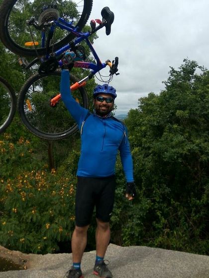 A rider celebrating the climb by lifting his blue MTB high.
