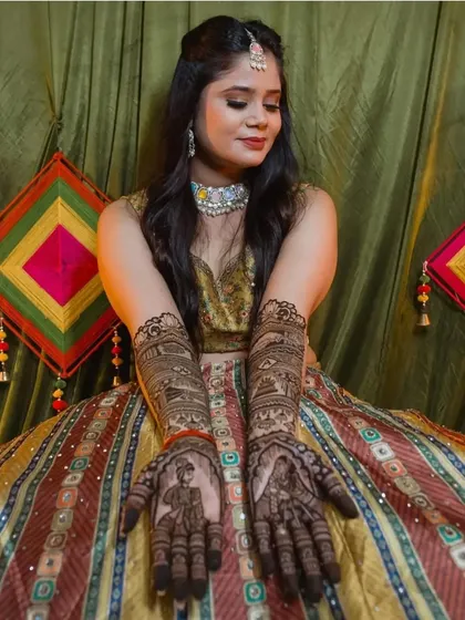A close-up of the beautiful mehendi design, with the colorful striped lehenga providing a perfect backdrop.