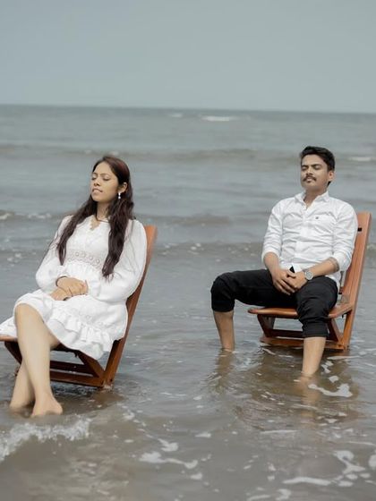 A serene and slightly playful moment with the couple relaxing in chairs as the tide comes in, capturing a unique beach experience.