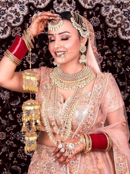A joyful bride in a peach-colored lehenga, adorned with heavy jewellery and kalire. This shows a complete rental look from head to toe.
