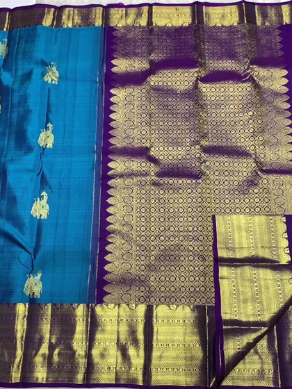 An authentic Kanchipuram handwoven silk saree, certified with the Silk Mark for purity. This piece showcases traditional elephant motifs woven with pure 2g zari against a beautiful blue silk, paired with a rich purple pallu.