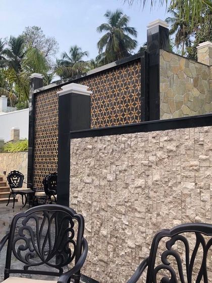 A close-up of an outdoor seating area, showcasing the interplay of different materials and textures. The combination of rough-cut stone walls, patterned screens, and smooth paving creates a rich, tactile experience within the garden landscape.