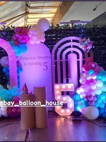 A magical unicorn-themed party setup with illuminated unicorn props, pastel balloon arrangements, and a light-up number "5".