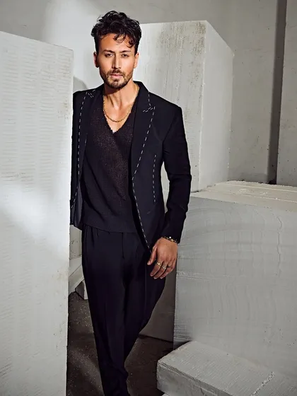 Tiger Shroff in a sleek, all-black Tisa Studio suit. The subtle white stitch detailing on the blazer adds a modern, deconstructed touch to this powerful look.