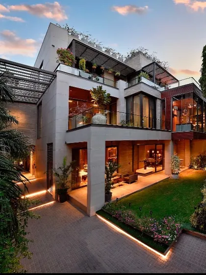 This modern home in Gurgaon showcases how to create a private sanctuary within an urban context. The design uses stacked volumes, terraces, and large glass openings to maximize light and green views, creating a warm, luxurious space that steps back from the city's pace.