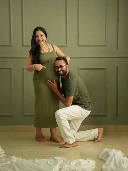 A fun and sweet pose! The father-to-be listens to the baby bump, creating a playful and heartwarming memory in the studio.