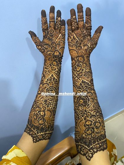 This design features a beautiful scalloped border, adding an extra touch of elegance to the full-arm mehendi.