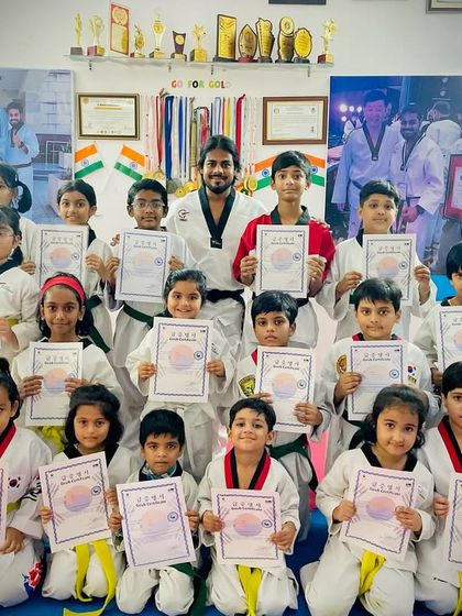 A full class of students proudly displaying their new yellow and green belts and certificates. This is a testament to their hard work and the guidance of their coaches.