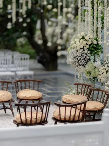 An intimate seating area at an all-white wedding, with chairs arranged amidst a sea of flowers.