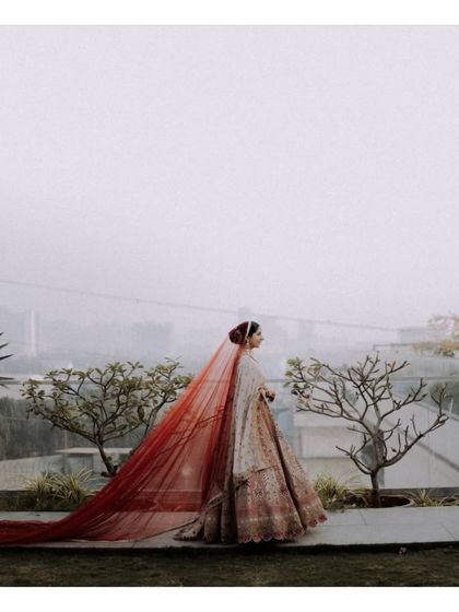 A stunning solo portrait of the bride, but it tells a story of romance. The flowing red veil against the city skyline creates a powerful, cinematic image.