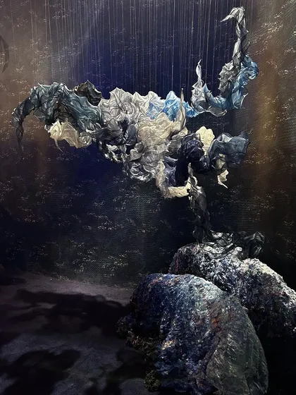 A dramatic sculpture from 'Into The Deep', where fabric forms appear to float above rocks like a mysterious sea creature. The piece captures the awe-inspiring and sometimes haunting beauty of the ocean.