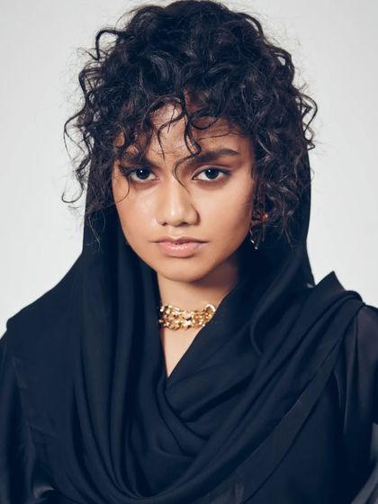 A moody and atmospheric editorial shot. I created a raw, textured hairstyle with messy curls and used a kohl-rimmed eye to give an intense, captivating gaze suitable for a high-fashion story.