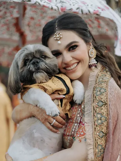 An adorable and heartwarming moment between the bride and her pet dog, who is dressed for the occasion. This candid shot is a favorite for all pet-loving couples.